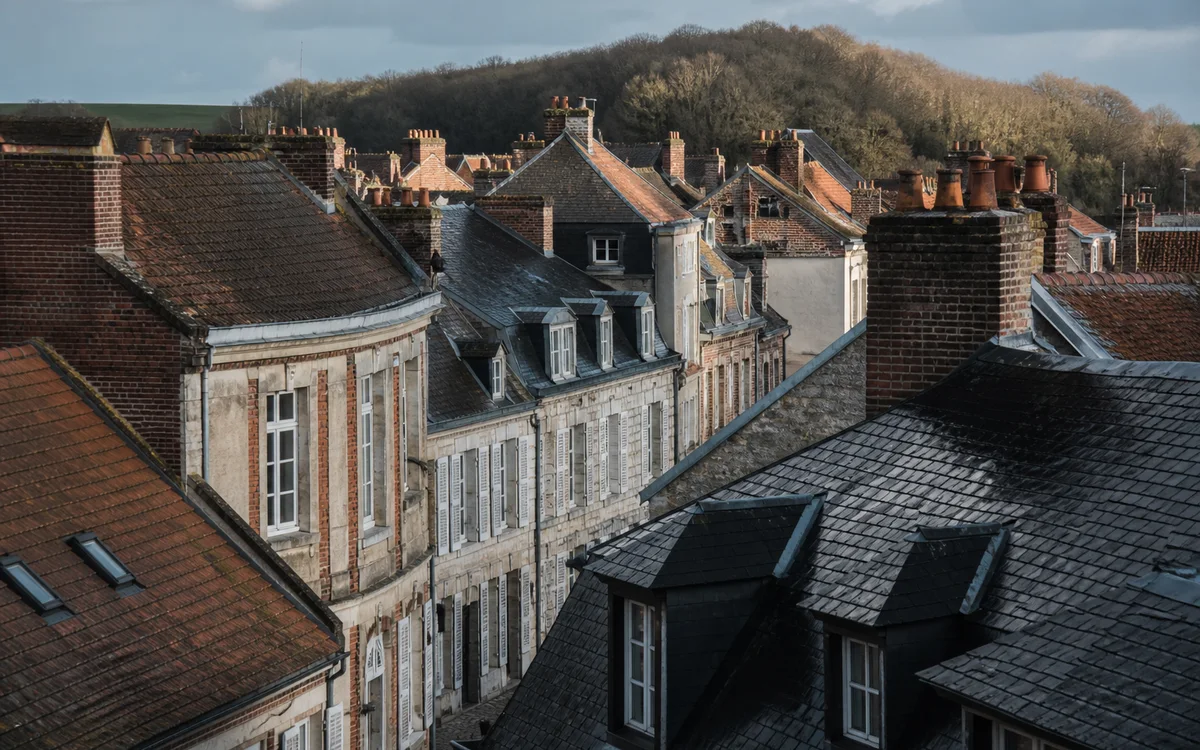 Toitures des Hauts-de-France Alignement de toitures en brique et ardoise dans les Hauts-de-France sous une lumière douce